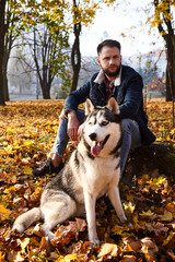 Hipster stylish guy with his husky dog in autumn forest.Pedigree dog concept. Best friends. Unconditional love. Guy enjoy walk with husky dog. Siberian husky cool pet. Selective focus