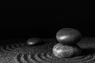 Fototapeta na wymiar Black sand with stones and beautiful pattern against dark background. Zen concept