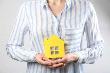 Woman holding coins and house model, closeup