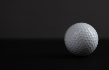 white golf ball on black background copy space