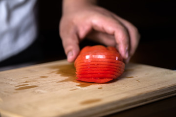 Chef cuts fresh tomato