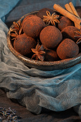 Craft chocolate truffles on plate with cocoa powder and anise, cinnamon, cardamom.