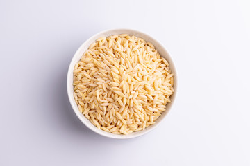 Orzo pasta, isolated on white background. Italian orzo pasta shaped like grains of rice, copy space, soft light