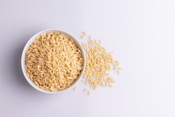 Orzo pasta, isolated on white background. Italian orzo pasta shaped like grains of rice, copy space, soft light