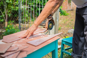 man working at home cutting tile with chainsaw on a makeshift table