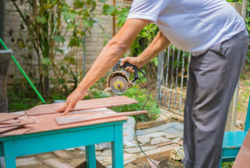man working at home cutting tile with chainsaw on a makeshift table