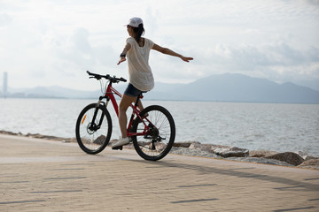 Fototapeta premium Woman cyclist riding Mountain Bike on sunrise seaside