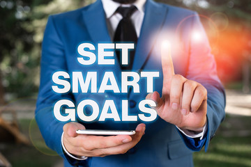 Conceptual hand writing showing Set Smart Goals. Concept meaning Establish achievable objectives Make good business plans Businessman with pointing finger in front of him