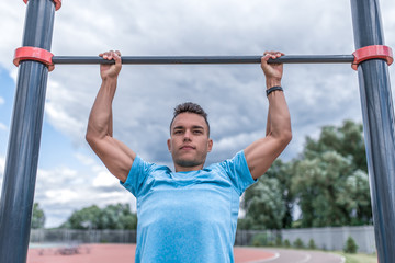 Fototapeta na wymiar Young sportsman, male athlete, pulls himself up on bar, in the summer day in the city, workout fitness, active lifestyle of modern youth, sportswear. Motivation for life.