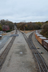 Fototapeta premium Looking down on rail cars loaded with gravel. Multiple train car on the tracks. Sitting in a railroad yard, multiple train tracks are in view. Lot of track switches.