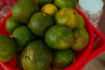 Green limes in a red plastic basket