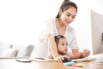 Mother watching her daughter who is learning to use the computer.