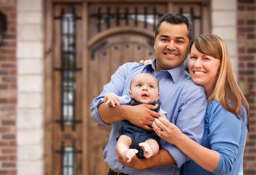 Happy Mixed Race Couple with Baby in Front of House