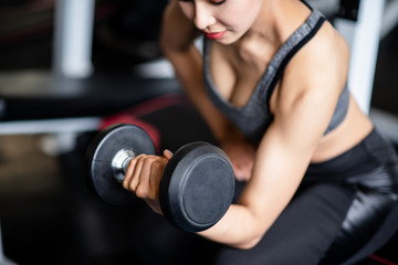 Fototapeta na wymiar Young healthy woman lifting dumbbells in the gym