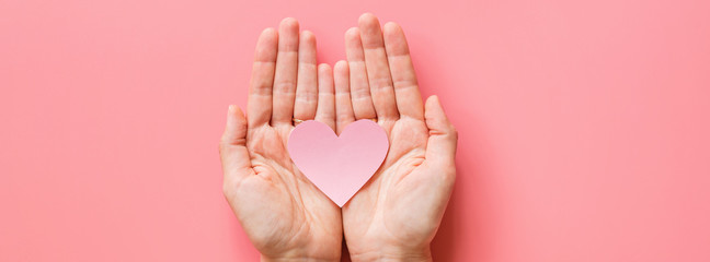 Valentine's day background. Female hands holding pink hearth. Flat lay, top view, mockup, template, copy space. Minimal abstract composition for 14 February celebration