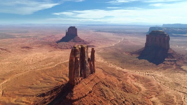 Aerial 4K footage of Navajo Tribal Park with its famous red flat rocks known as mitten buttes. Popular place for moviegoers. Camera approaches one of the rocks from the air.