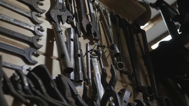 Tracking shot of classic wrenches hanging on a wall.