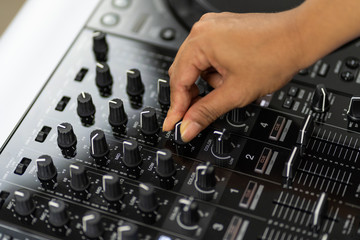 Hands of DJ mixing tracks on professional sound mixer.Fashionable rings on fingers of girl disc...