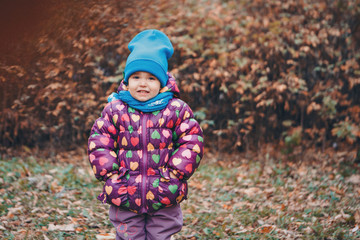 a small child with mother in a warm suit walks in the woods. autumn park. The concept of children's fashion, accessories, outdoor walks