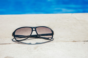 glasses on a stone slab by the pool close-up. the concept of advertising accessories, beach holiday