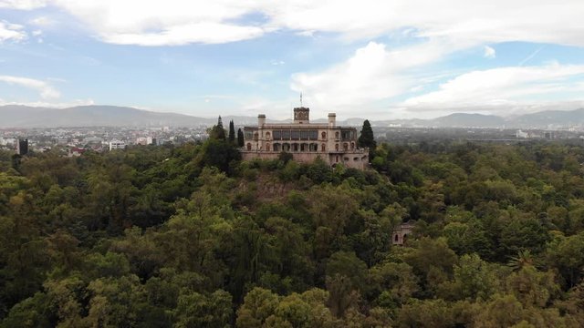 Aerial view of Chapultepec Castle in Mexico City at sunrise. Drone flying forward with a blue sky as background