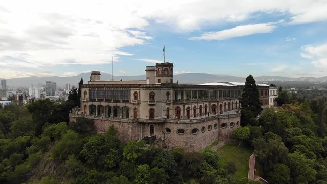 Revealing Mexico City skyline behind the Chapultepec Castle at sunrise, drone slowly ascending