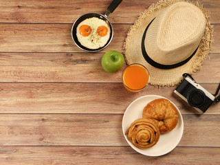 Top view of breakfast set and traveler accessories on wooden table.