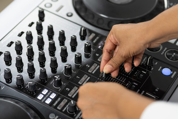 Fototapeta na wymiar Hands of DJ mixing tracks on professional sound mixer.Fashionable rings on fingers of girl disc jockey playing music.Closeup,knobs and regulators in focus.Girl dj play music tracks at house party