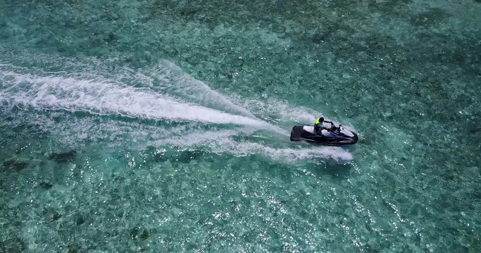 Young man with ski jet tracing clear crystal water of shallow lagoon, water sports activities on vacation days in Hawaii