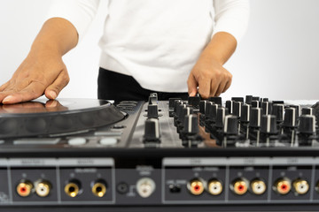 Fototapeta na wymiar Hands of DJ mixing tracks on professional sound mixer.Fashionable rings on fingers of girl disc jockey playing music.Closeup,knobs and regulators in focus.Girl dj play music tracks at house party