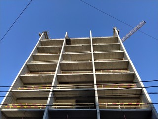 building under construction. High rise construction made of concrete against the blue sky