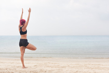 Fototapeta na wymiar Girl doing yoga on the beach in the early morning