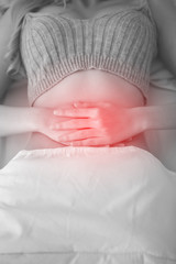 Young woman having a period cramps or period pain or stomachache lie down on her bed