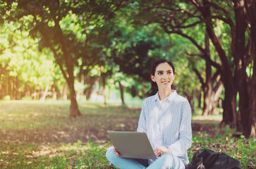 Beautiful young woman using laptop computer at public park in the morning,Happy and smiling,Relaxing time,Positive thinking