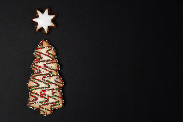 Christmas tree biscuit with hazelnut star on black background - top view with copy space