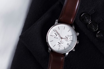 dark brown leather men's watches with white display with a black coat and white shirt as background