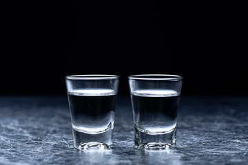 Vodka in a shot glass on metallic silver texture background prepared for a party