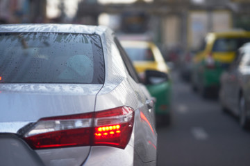 Water frost and dropets on rear wind shield of sedan car on rainy season on traffic background