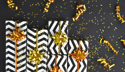Gifts with golden ribbons and glitters on black background.