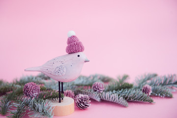 christmas decoration on a pink background - toy bird, fir branches, cones