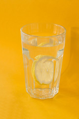 glass of lemoned water on yellow background