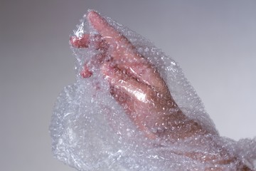 young womans hand covered in transparent air bubble plastic wrap