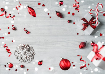 Merry Christmas and New Year background. Xmas holiday card made of flying decorations, fir branches, red balls, snowflakes, sparkles, bokeh, light on wooden background. Selective focus