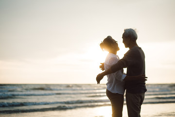 Romantic loving senior caress beloved husband cuddling and looking in eyes. on beach during sunset...