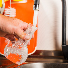 A man pours tap water into a glass flask.