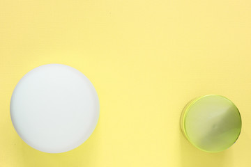 Cosmetic jars on a yellow background. Health and beauty. Top view, copy space