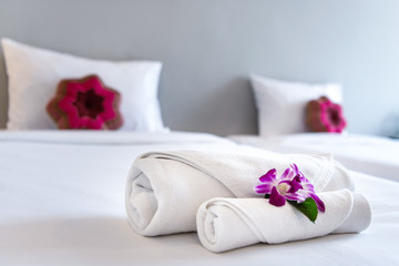 Towel with Orchid on bed decoration in bedroom interior for hotel customer.