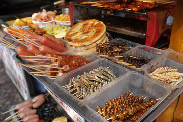 A stall that selling naxi style snack like baba pancake, insects, dried meat sausage, fried little fish and worms.