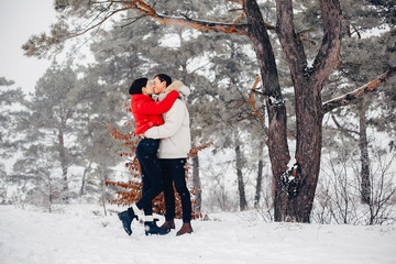 Young couple in a winter park. Man with a red sharf. Lady in a red jacket