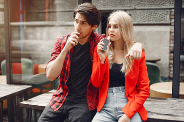 Stylish couple in a city. Two people use the electronic cigarette